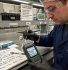 Teknisi QC melakukan self-check moisture meter - pembersihan probe sensor dan pengecekan display dengan logbook verifikasi